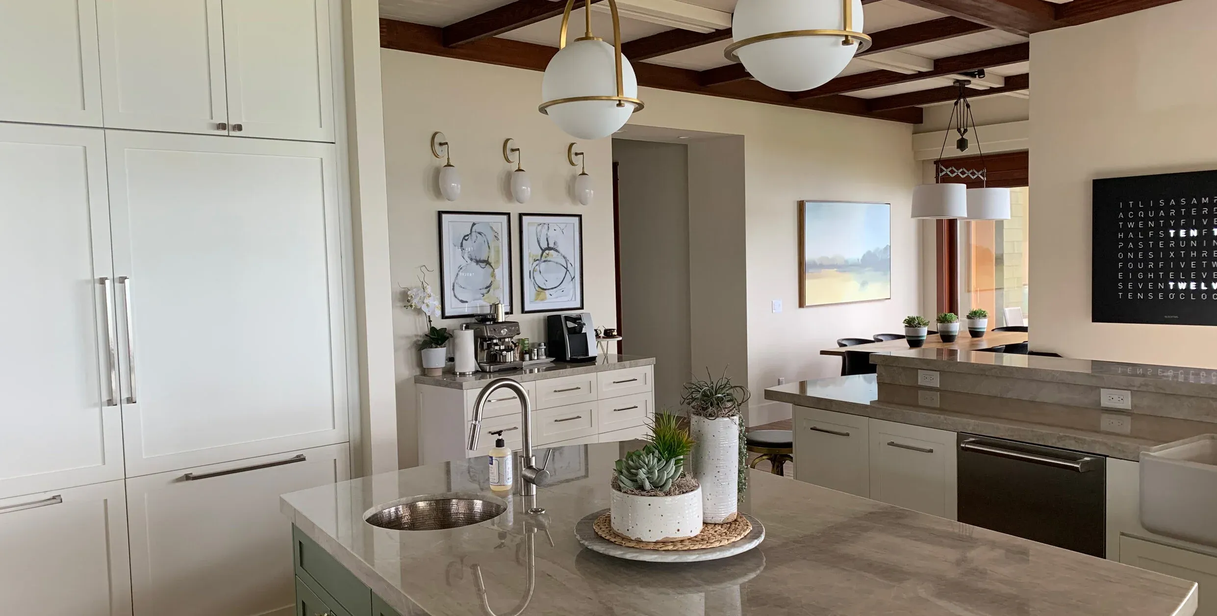 A kitchen with globe pendants under wood beams